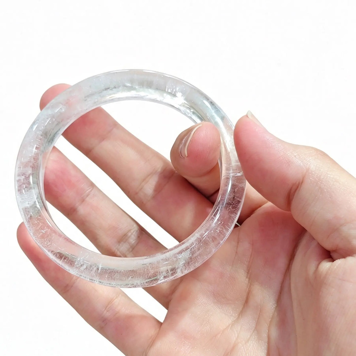Natural translucent clear quartz gemstone bangle bracelet held in hand showing ice crystal veils