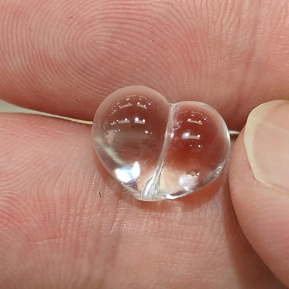 Natural clear quartz carved puffy heart bead vertical drilled close up held in hand showing high clarity transparent crystal