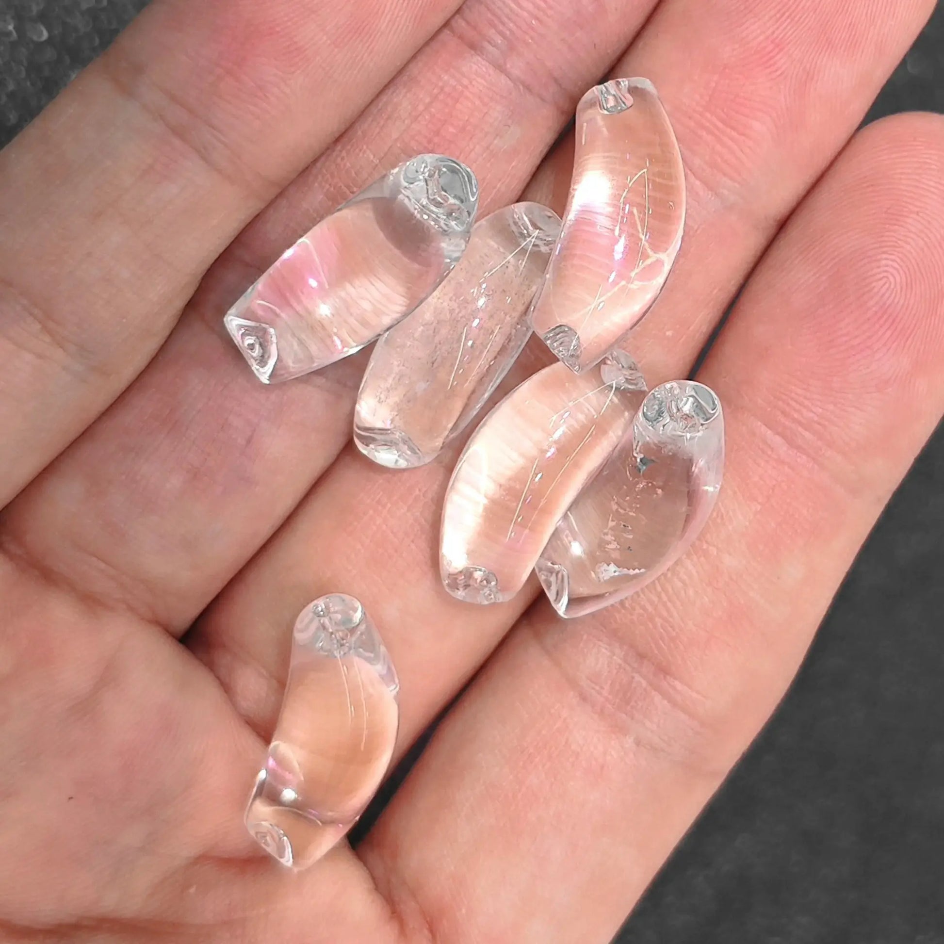 five natural clear quartz curved tube focal beads held together in palm