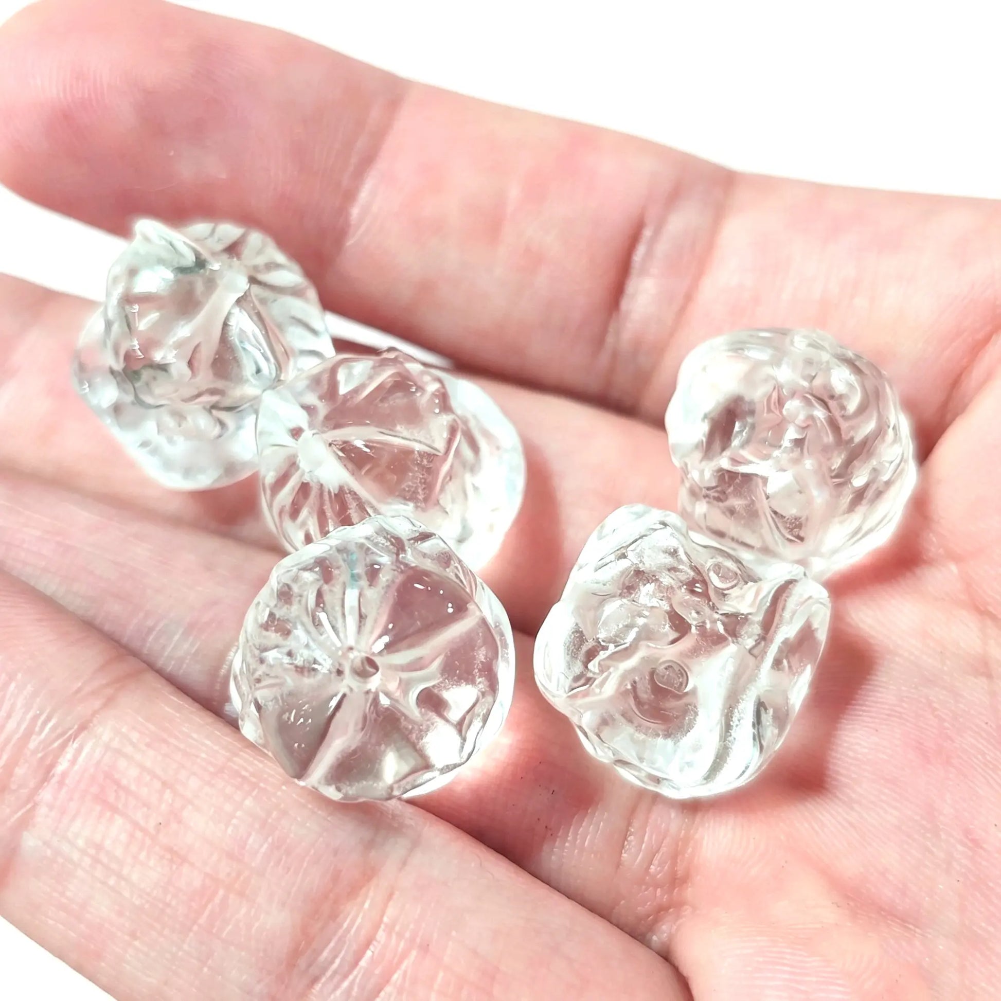 Natural clear quartz lion beads 15mm held in hand showing top-to-bottom vertical drill holes and carved lion details