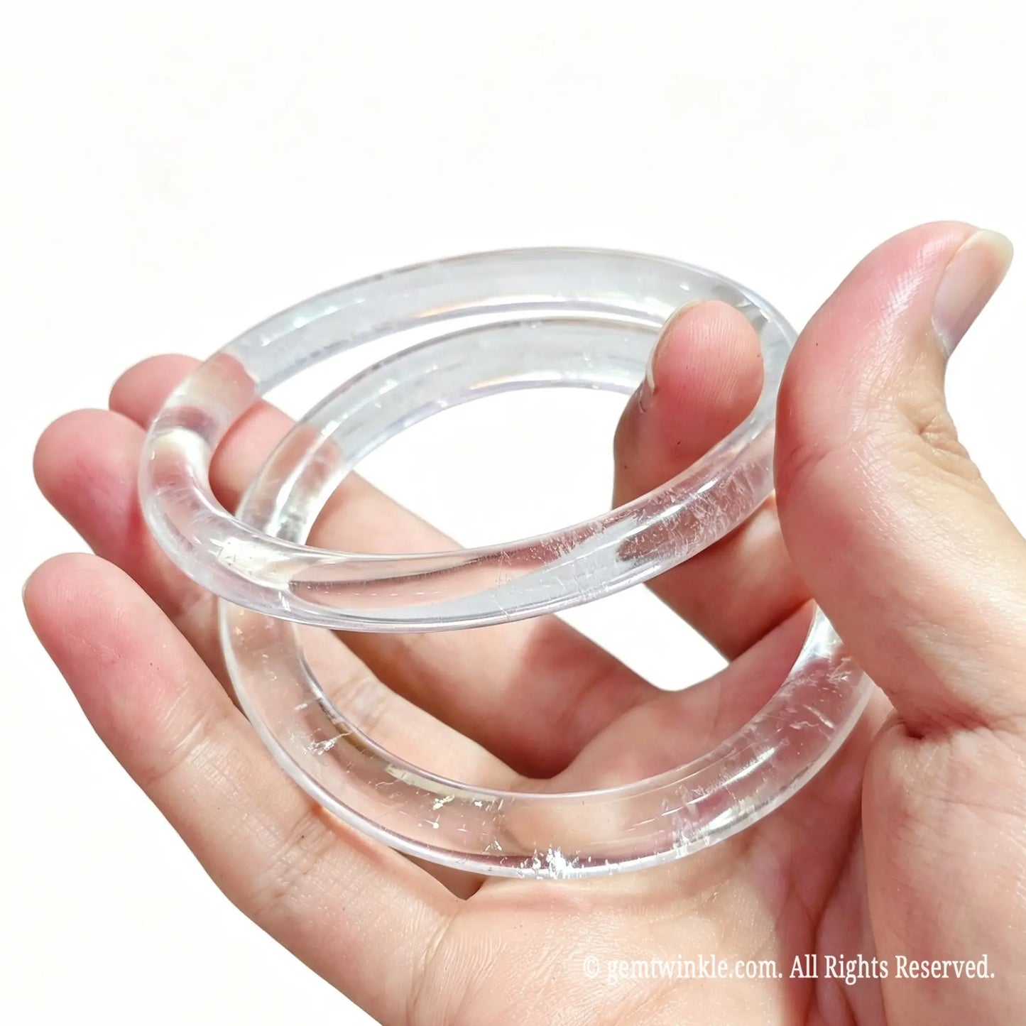 Side view of polished natural clear quartz slim bangle displaying liquid glass luster and optical clarity