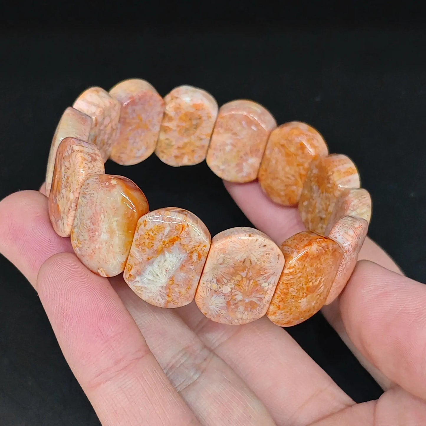 Natural fossil coral 20x14mm smooth rectangular block bracelet held close up showing orange tones and fossil flower patterns