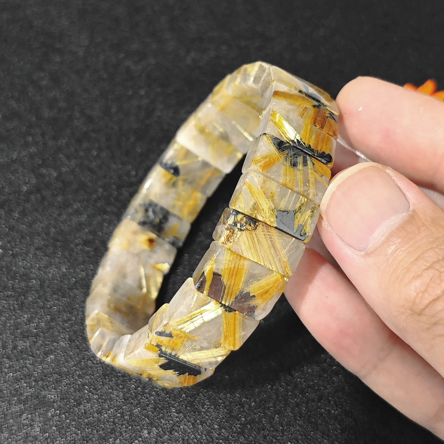natural golden rutilated quartz plate bracelet held in hand showcasing metallic rutile inclusions