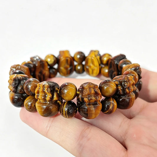 natural golden tiger eye pixiu carved bracelet held in hand showing silky golden brown chatoyancy and carved pi yao beads