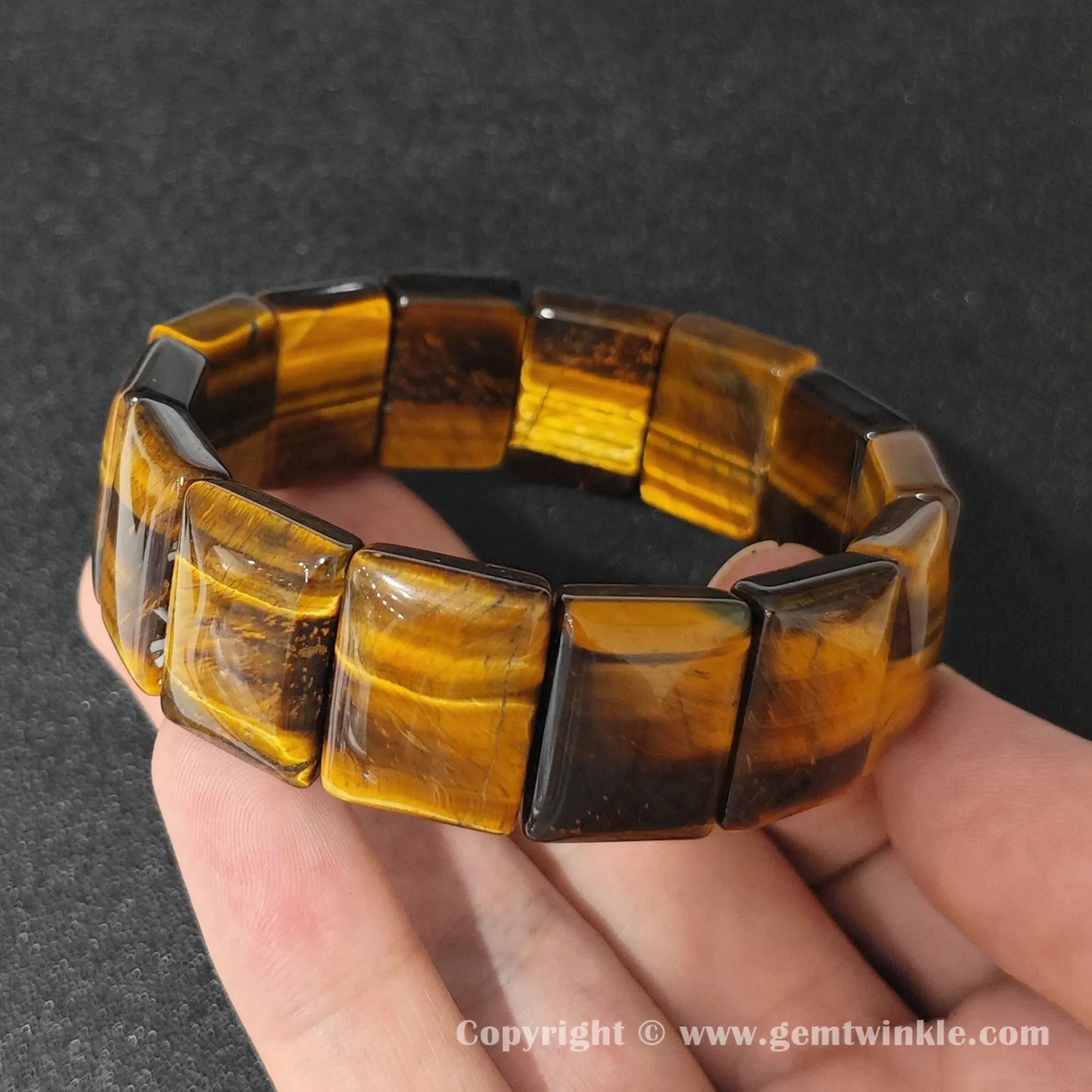 golden yellow tigers eye plate stretch bracelet held over open palm displaying rich chatoyant luster