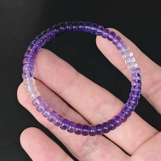 Natural gradient amethyst 5.5-6mm straight cut wheel bead bracelet held in hand showing purple to clear ombre transition