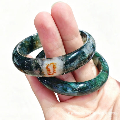 Two translucent natural moss agate bangles displayed in hand for crystal shop owners