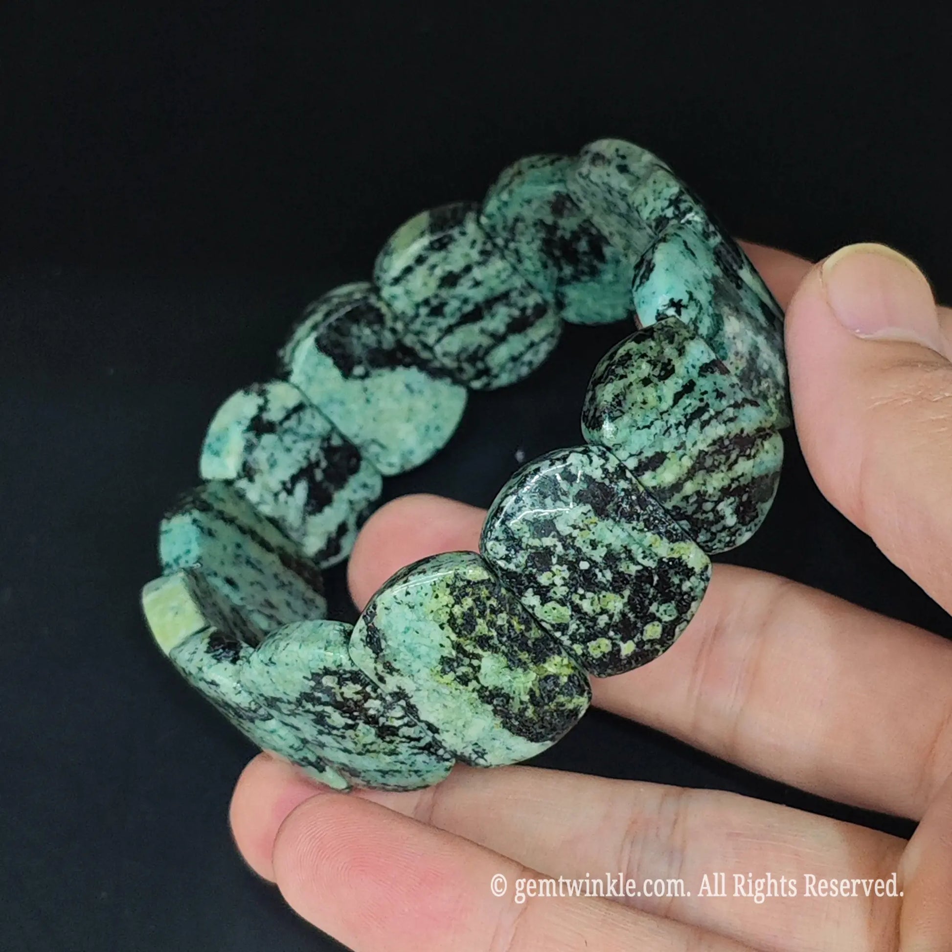 Full view of natural green peacock jasper 24mm block bracelet resting in hand highlighting unique mineral matrix patterns