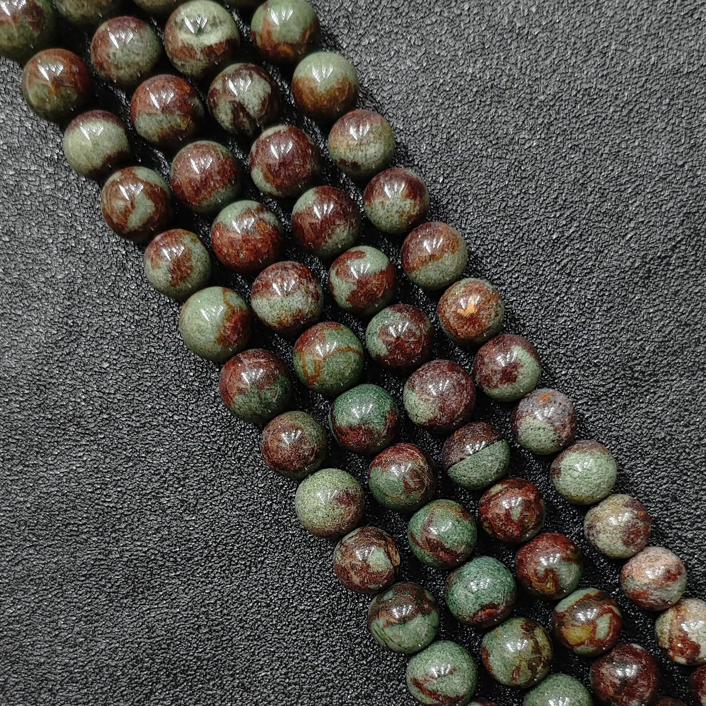 close up of natural green phantom quartz round beads with deep inclusions and red skin