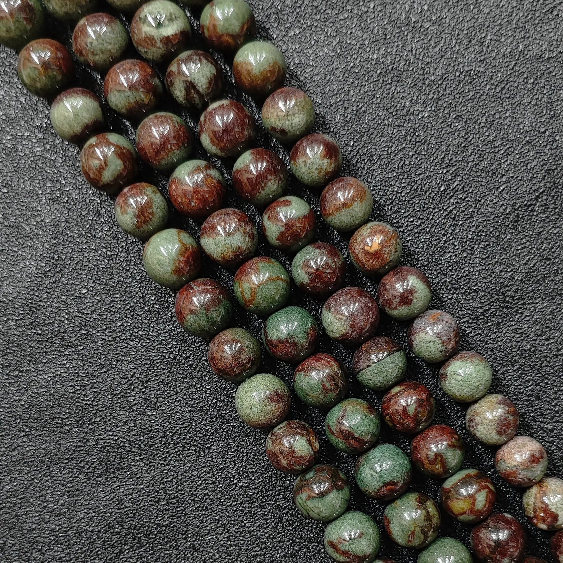 close up of natural green phantom quartz round beads with deep inclusions and red skin