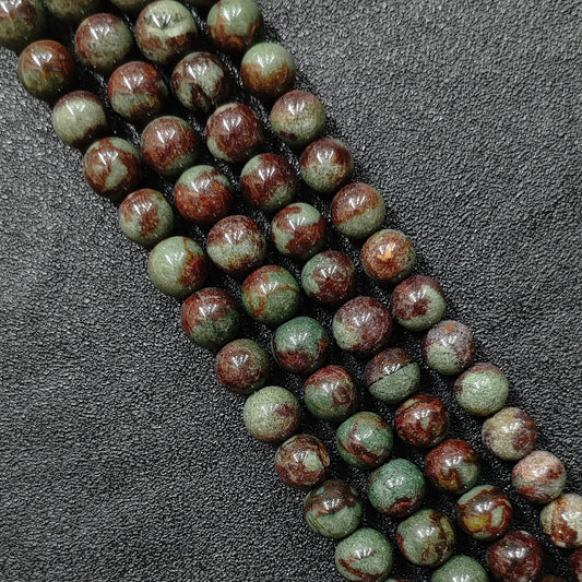 close up of natural green phantom quartz round beads with deep inclusions and red skin