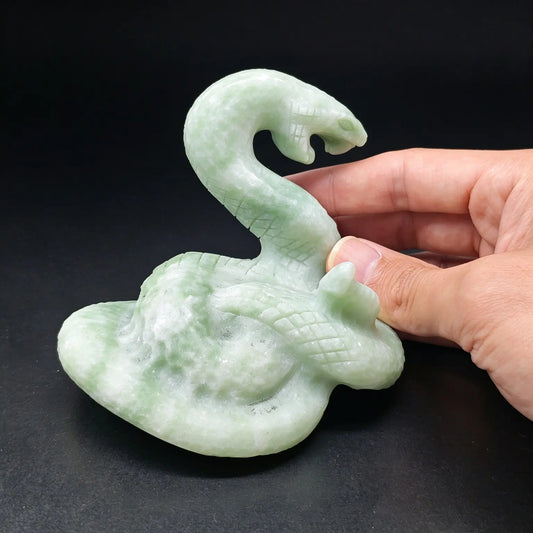 side profile view of natural green stone coiled snake statue held in hand displaying carved serpent head