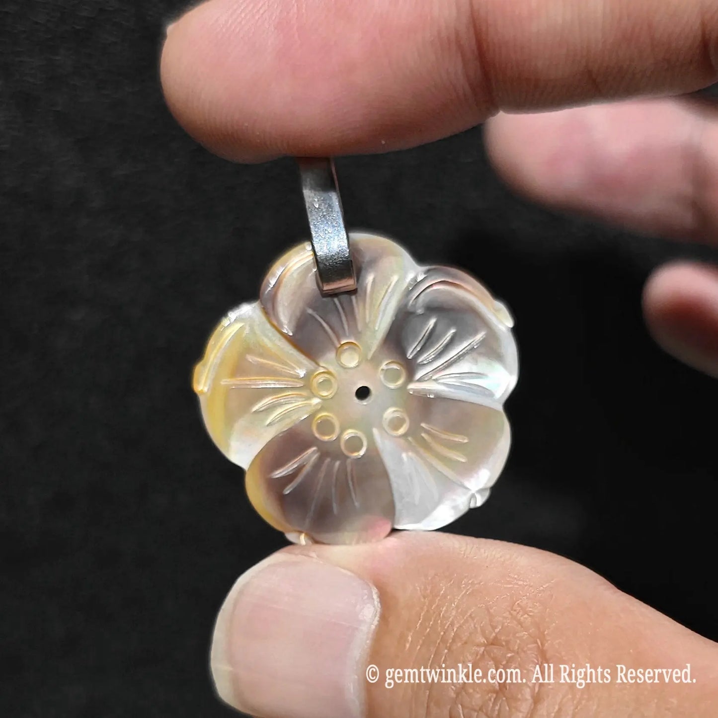 Side angle display of 25mm grey shell flower pendant held in hand showcasing smooth carved contours and bail attachment