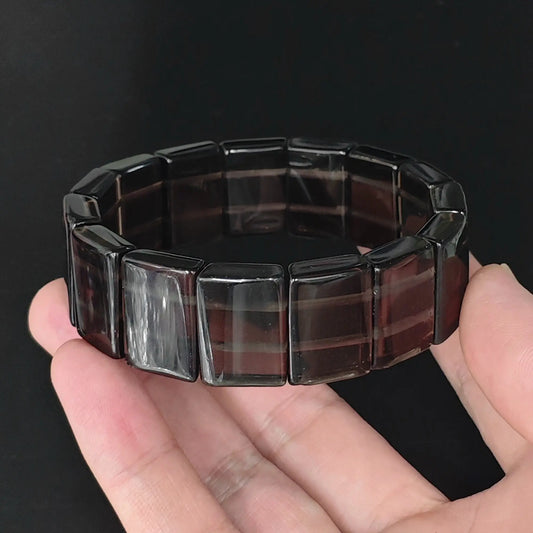 Natural ice obsidian 20x15mm rectangle plate bead bracelet held in hand revealing translucent smoky glass clarity