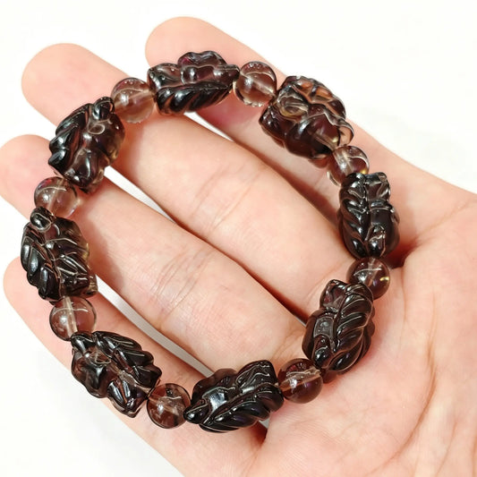 natural ice obsidian nine tailed fox carved bracelet held across hand showing translucent smoky fox beads