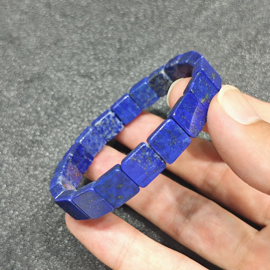natural lapis lazuli square tile bracelet held between fingers showing royal ultramarine blue and golden pyrite inclusions