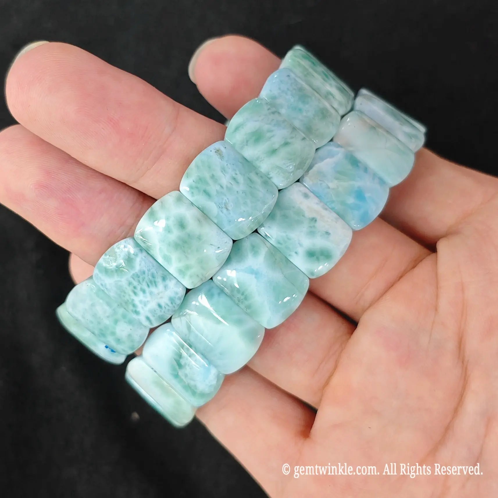 Hand displaying a natural larimar bead stretch bracelet formatted for small shop inventory