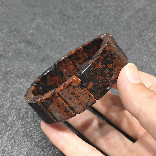 natural mahogany obsidian rectangle tile bracelet held in hand showing deep black obsidian and mahogany red volcanic matrix