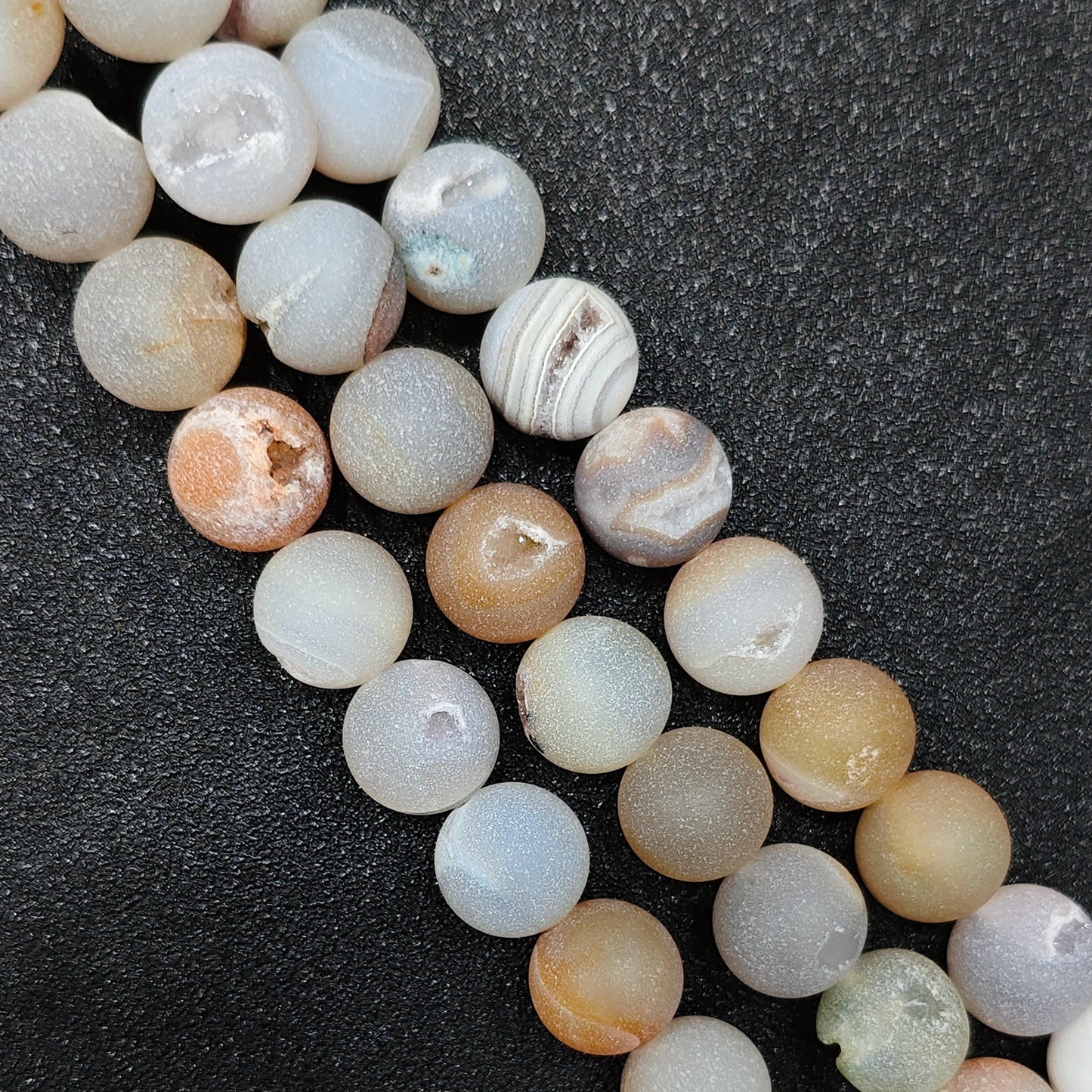 Close up view of natural matte druzy agate geode loose beads in 12mm diameter showing exposed caves with tiny quartz crystal clusters wholesale sourcing