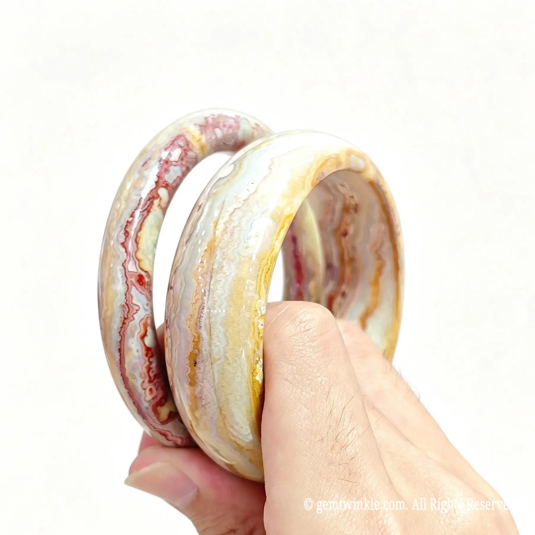 Hand holding natural mexican crazy lace agate bangles with intricate swirl patterns