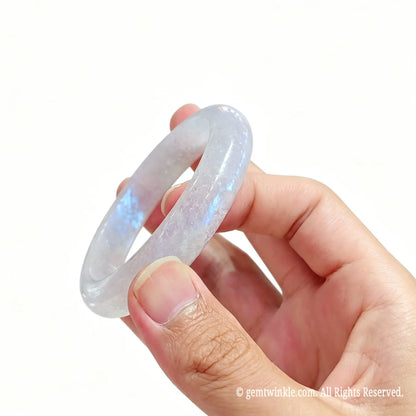 Side view of polished natural moonstone bangle displaying glossy surface finish and light reflections