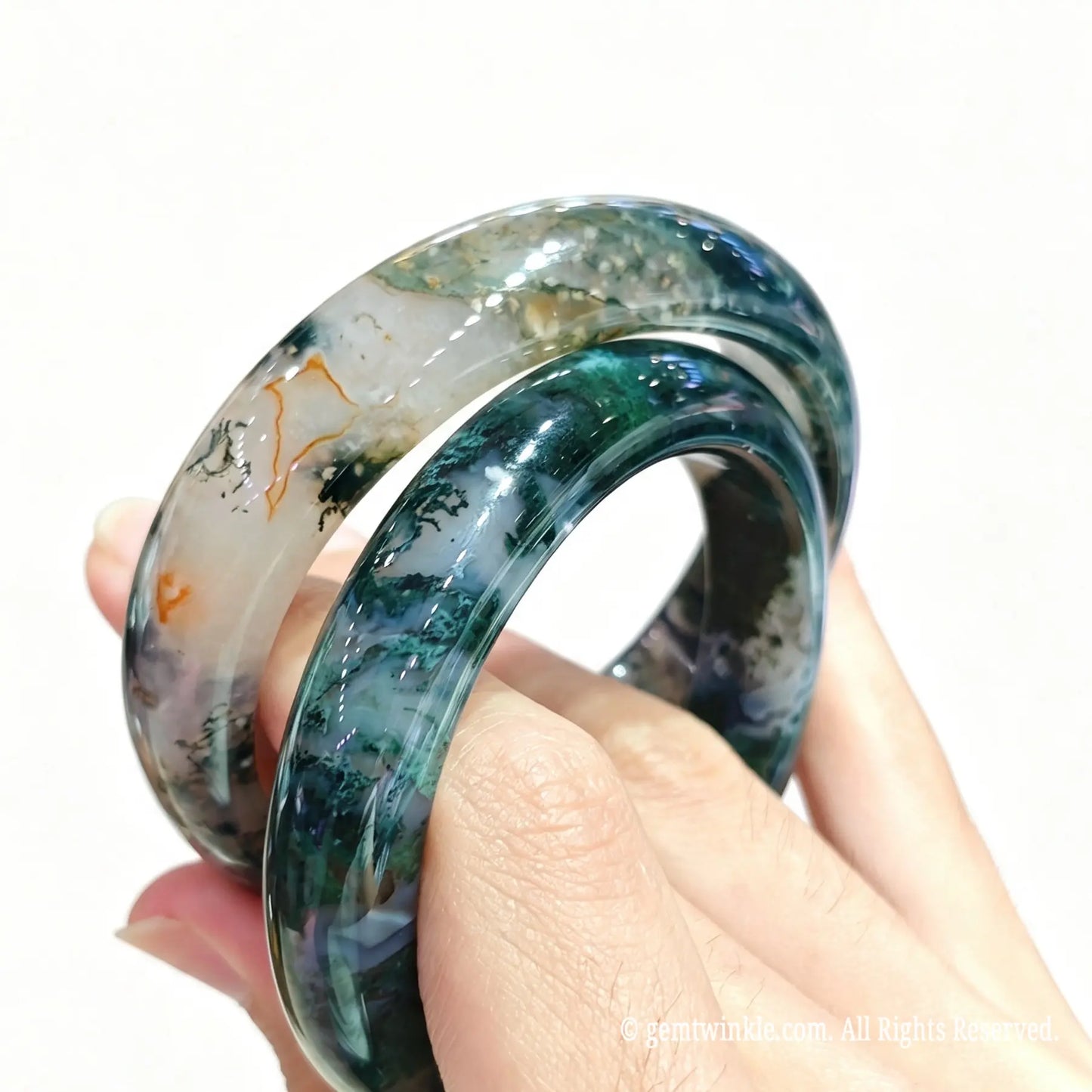 Natural moss agate gemstone bangle bracelet with green dendrite inclusions presented on hand