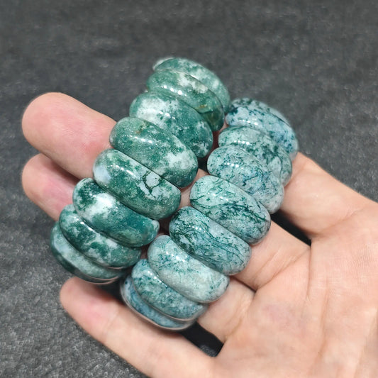 natural moss agate oval cushion bead bracelet pair held on fingers showing deep forest green mossy inclusions