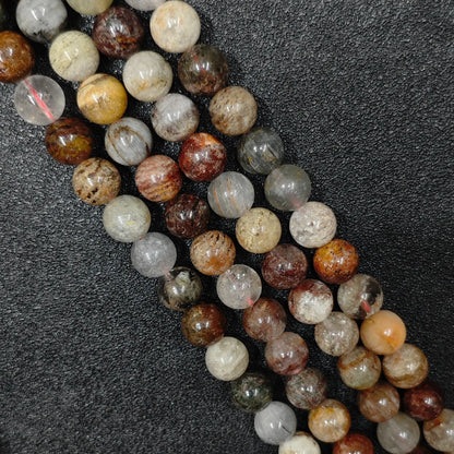 close look at 10mm natural multi color phantom quartz gemstone strands with rich scenic lodolite inclusions on black background