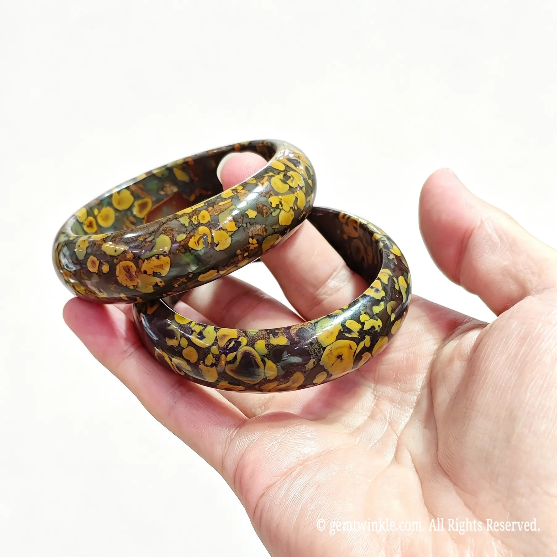 Hand displaying a pair of polished natural nuwa stone bangles for small shop inventory