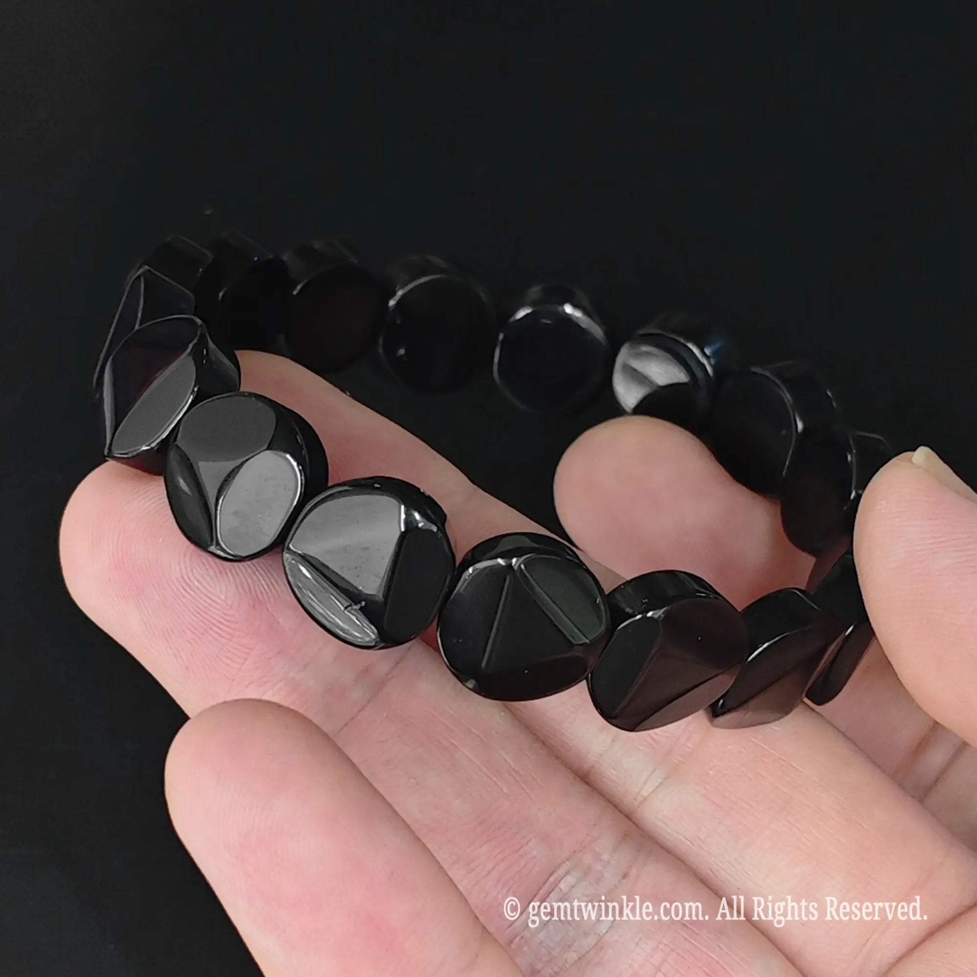 Full display view of natural obsidian 12mm geometric triangle cut coin bracelet highlighting glossy black surface reflection