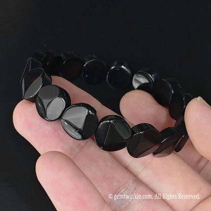 Full display view of natural obsidian 12mm geometric triangle cut coin bracelet highlighting glossy black surface reflection