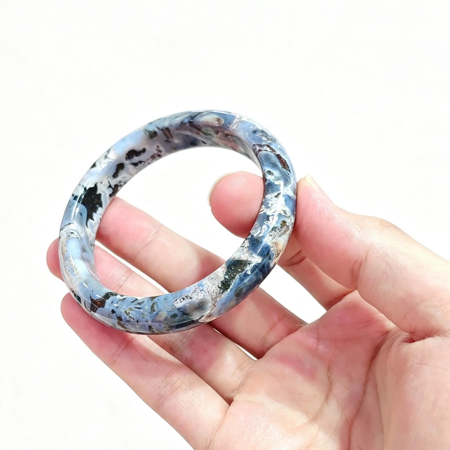 Hand holding natural ocean jasper bangle bracelet with distinctive blue-grey orbicular patterns