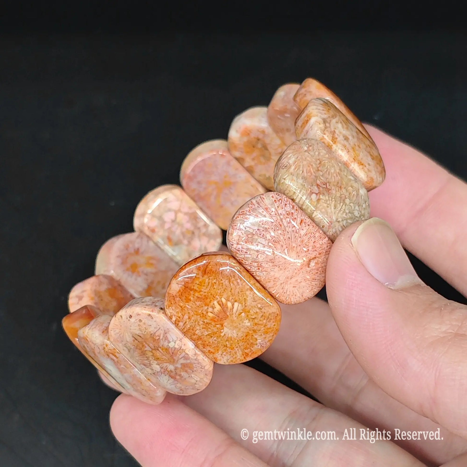 Full view of natural orange fossilized coral 20x14mm block bracelet resting in hand displaying unique prehistoric flower patterns