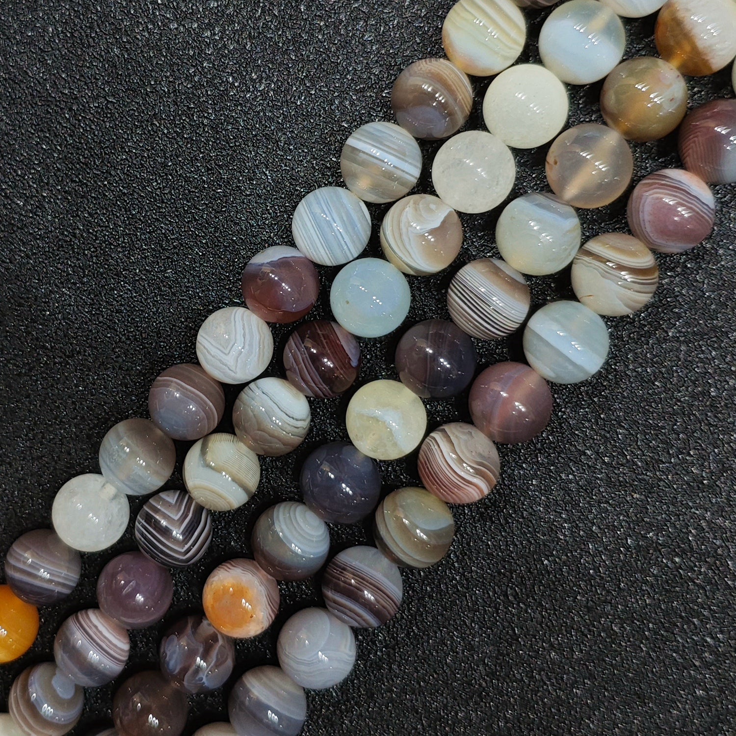 High polish natural un dyed persian agate round loose beads with prominent parallel silk stripes on black background for jewelry making