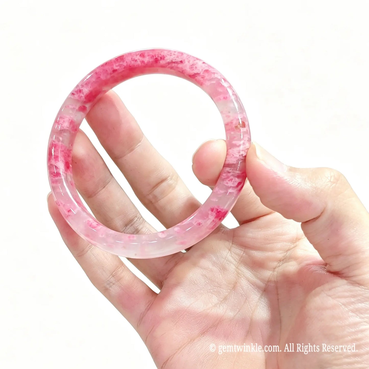 Two natural rose rhodonite bangles held together highlighting vibrant pink tones under studio light