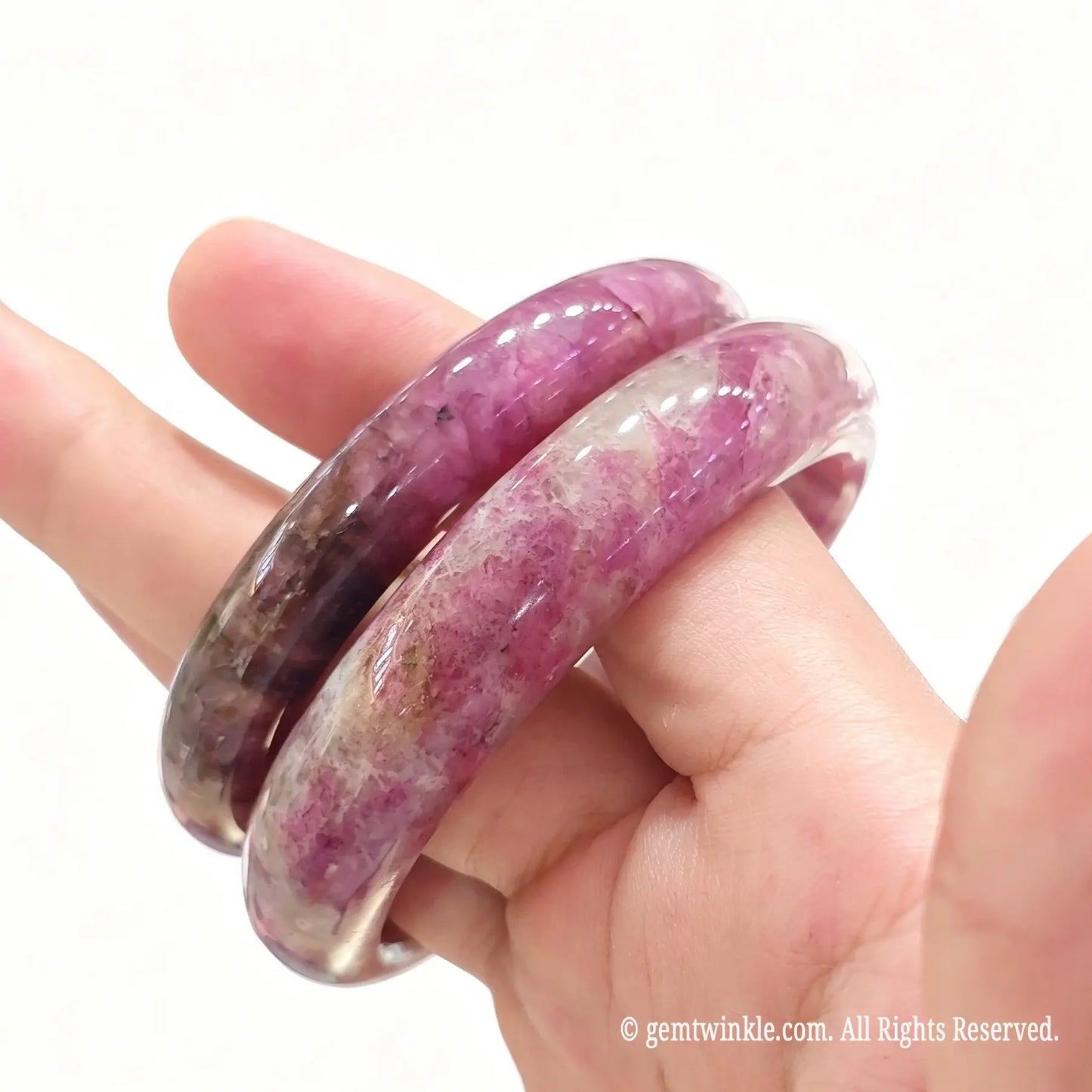 Pair of natural plum blossom tourmaline bangles held together showcasing magenta crystal clusters