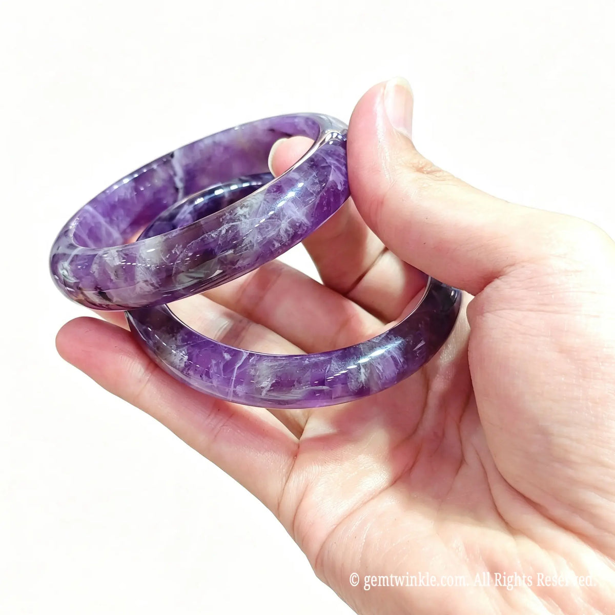 Side view of two natural chevron amethyst bangles showing glossy surface finish and natural white quartz veining