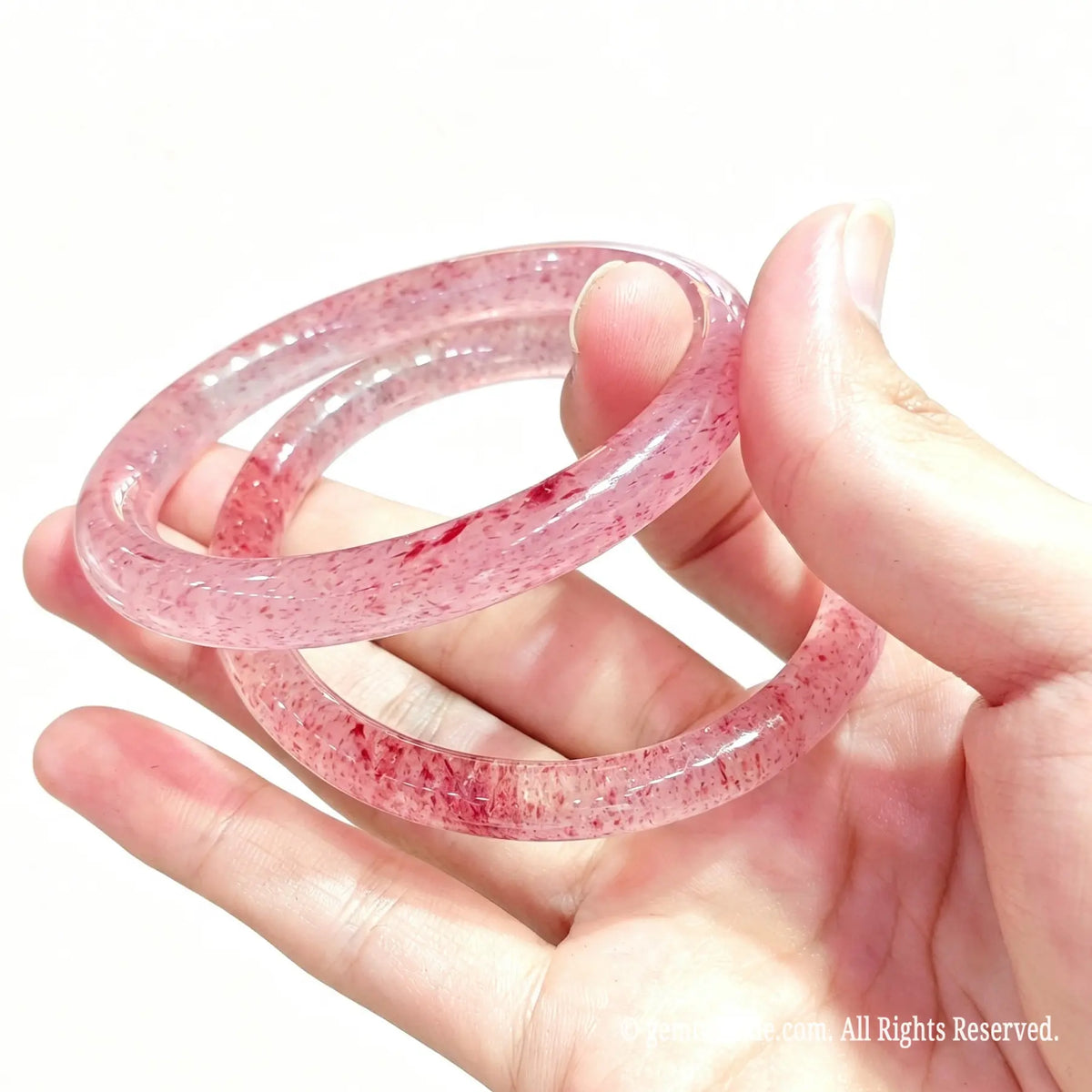 Side view of polished natural quartzite bangles held in hand displaying glossy surface finish