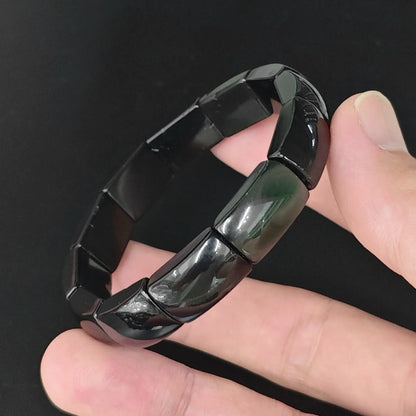 Natural rainbow eye obsidian bangle plate bead bracelet held in hand revealing subtle iridescent sheen on curved plate beads