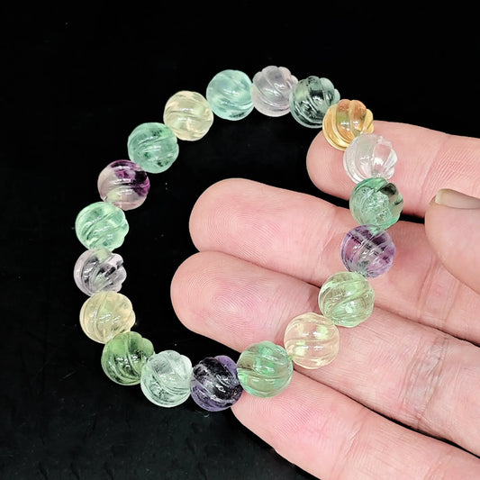 Natural rainbow fluorite 10mm pumpkin carved bead bracelet held close up showing multi color pastel tones and melon grooves