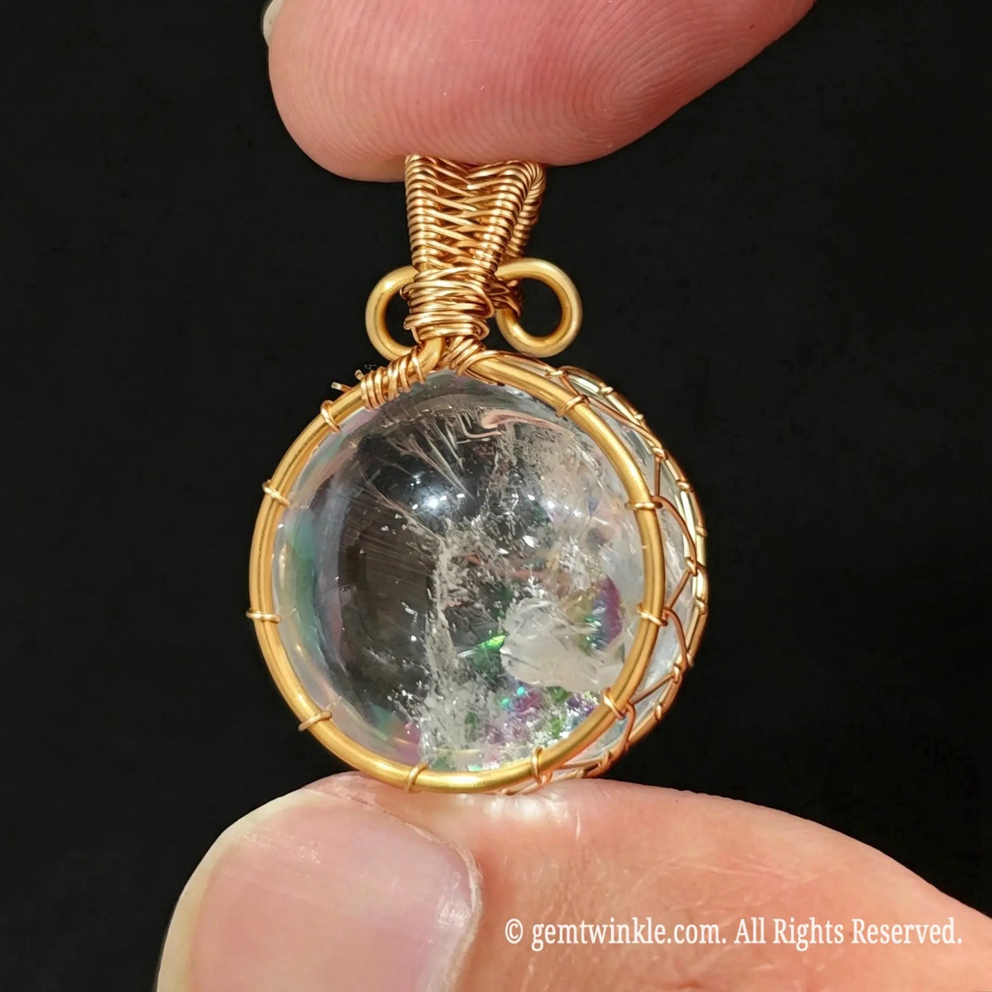 Front view of gold wire wrapped clear quartz sphere pendant showing transparent crystal ball and accent top bead