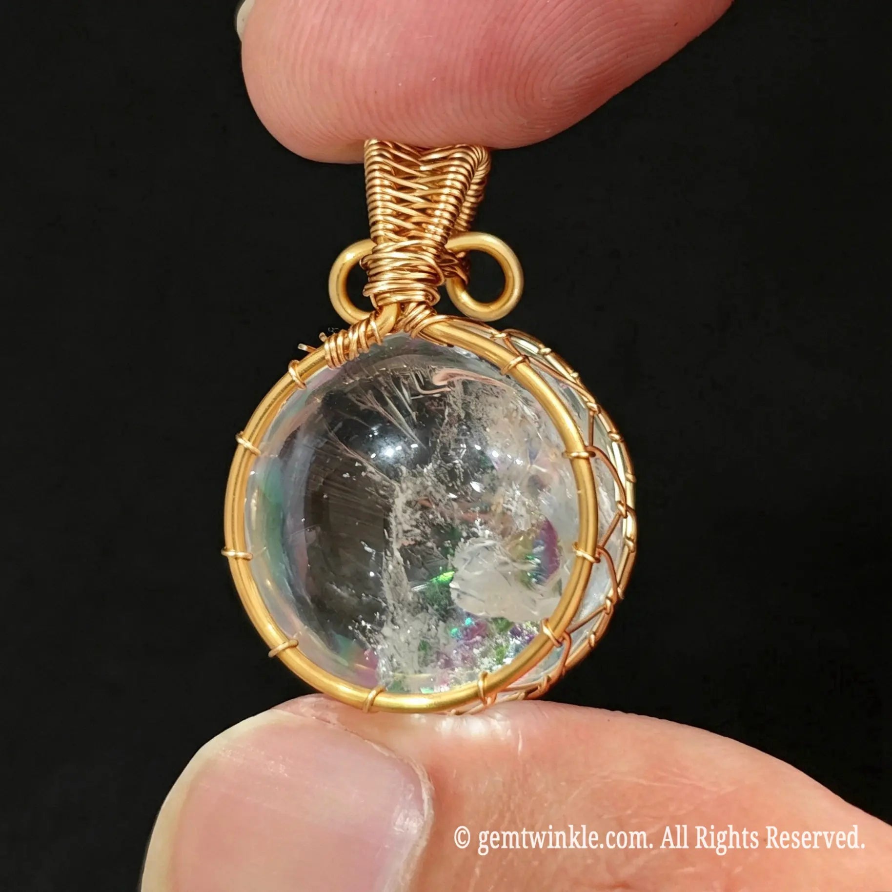 Front view of gold wire wrapped clear quartz sphere pendant showing transparent crystal ball and accent top bead