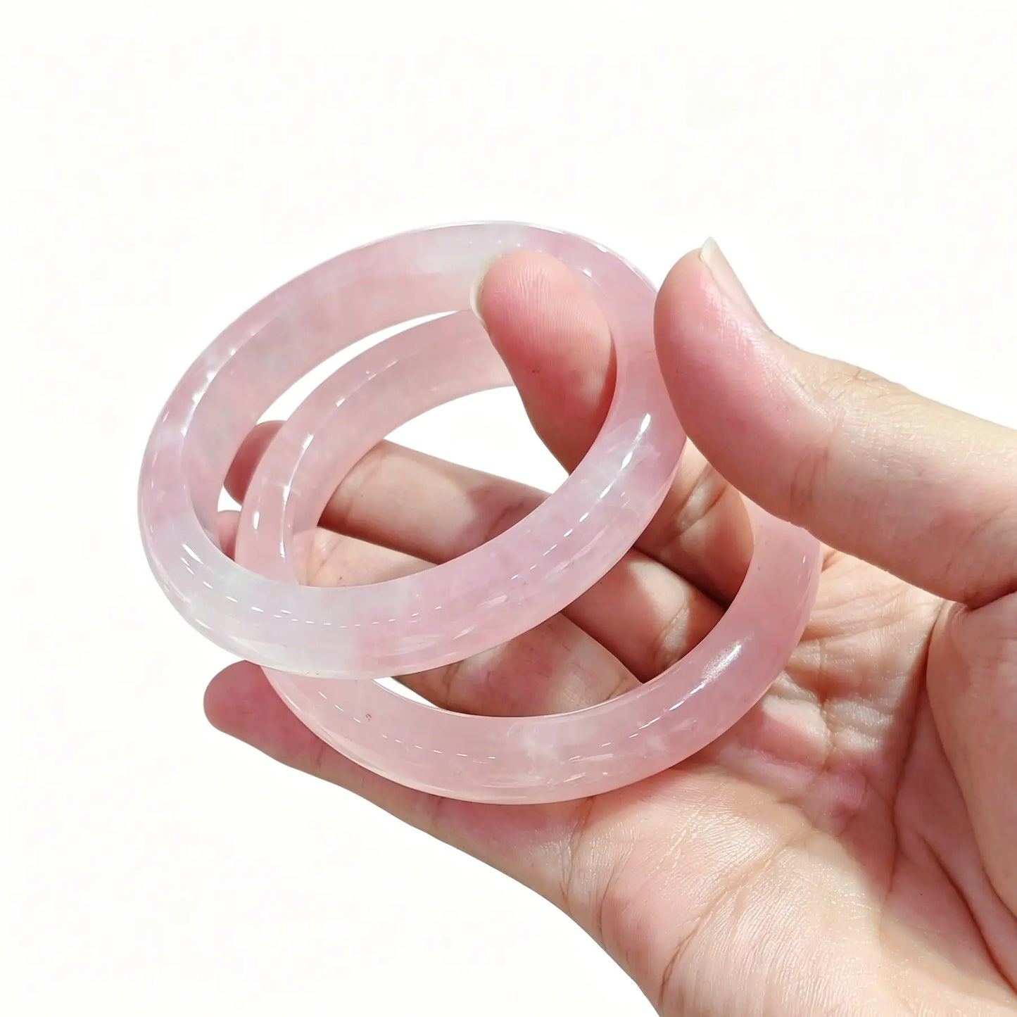 Hand displaying a pair of polished natural rose quartz bangles for small shop inventory