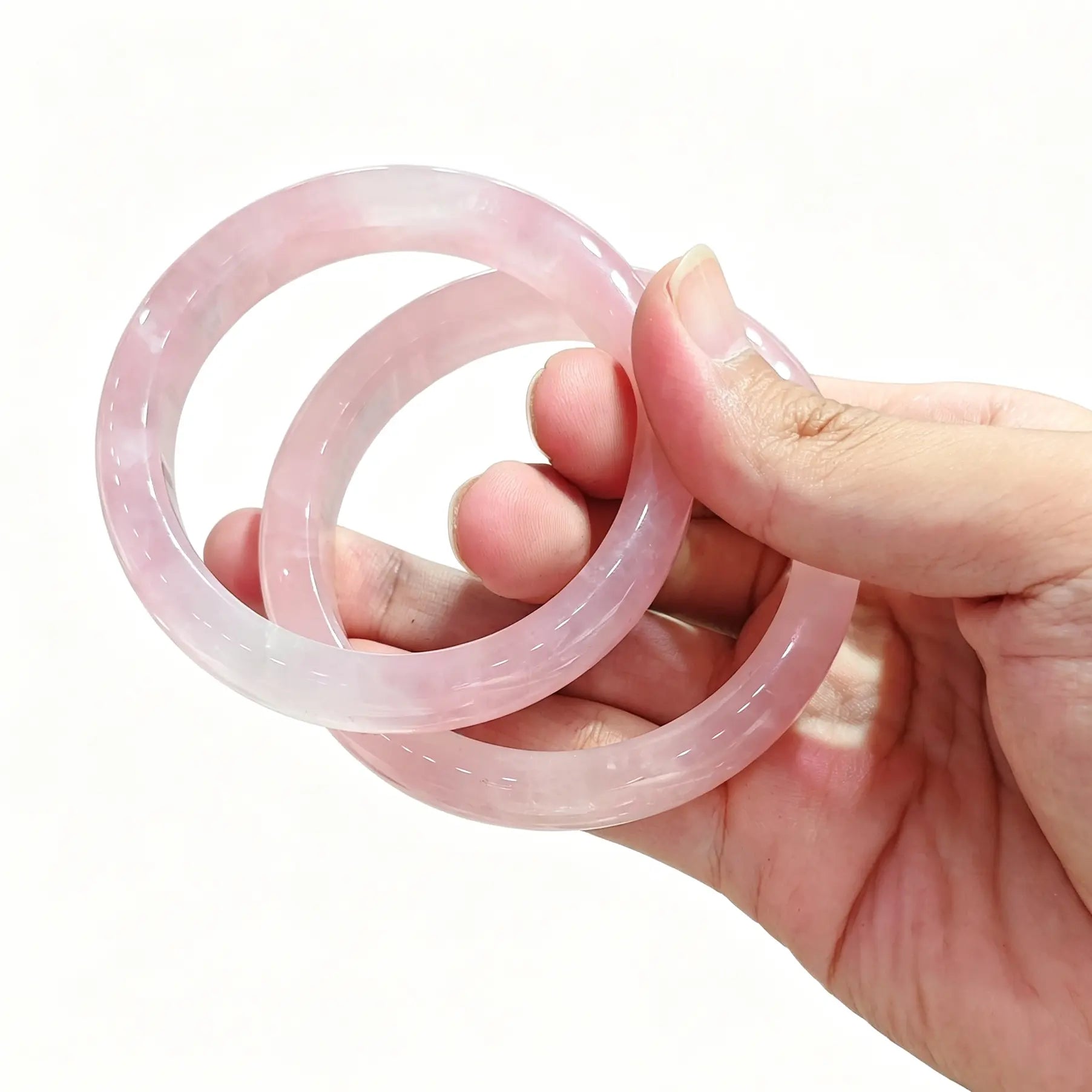 Side view of polished natural rose quartz bangle displaying high surface luster and natural crystalline veiling