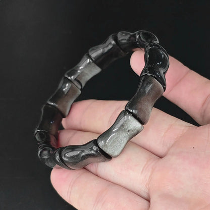 Natural silver sheen obsidian bamboo joint bead bracelet held in hand revealing bright silvery schiller flash