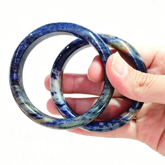 Hand holding a pair of natural sodalite bangles with rich royal blue and white calcite veins