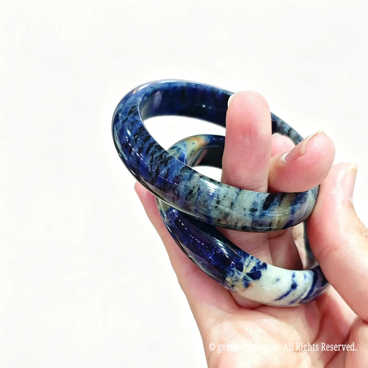 Side view of polished natural blue sodalite bangles highlighting glossy surface finish and white mottling