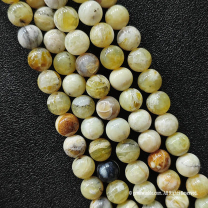 standard grade natural stones for jewelry making wholesale showing polished round yellow opal strands with rustic matrix patches