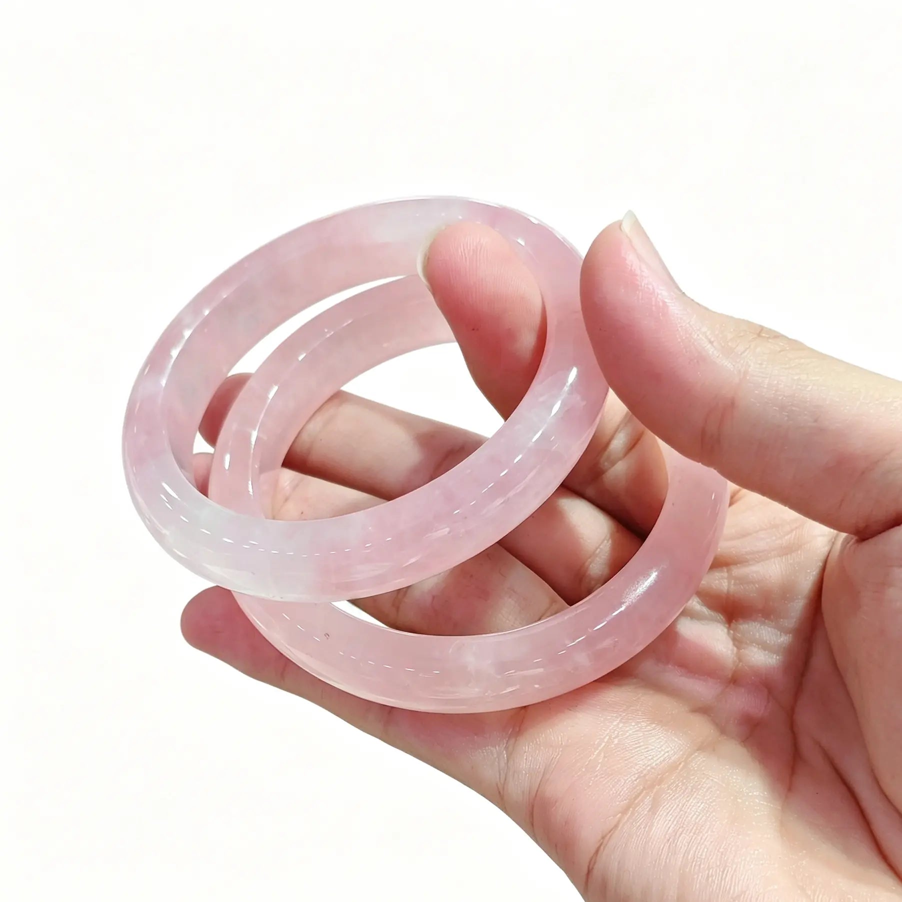 Two natural rose quartz bangles held together highlighting soft romantic pink tones under light