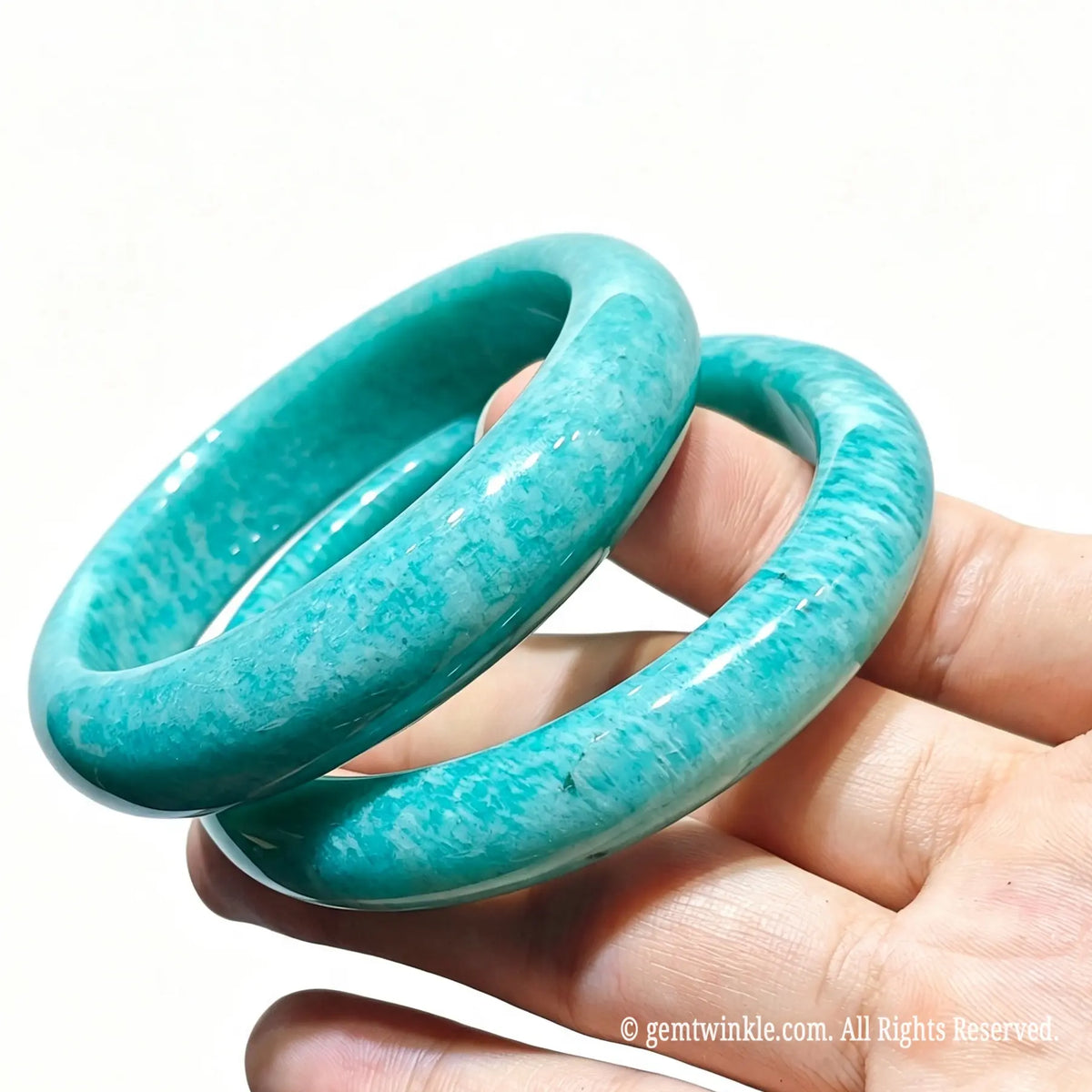 Two natural amazonite bangles held together displaying silky white streaks and ocean blue hue